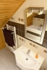 Rodinná koupelna v podkroví v kombinaci dřeva a praktického obkladu.