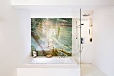 Ve stejných čistých liniích jako celý dům je provedena i koupelna, které dominuje velký barevný panel vyrobený z přírodního brazilského granitu s názvem „Botanic Green“, který připomíná abstraktní malbu.