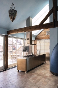 Nerezovou kuchyňskou linku zapuštěnou do stěny doplňuje elegantní ostrůvek. Ateliérová okna propouštějí do prostoru dostatek denního světla
