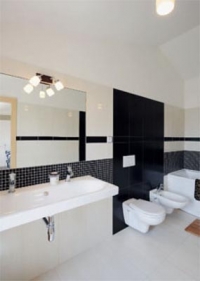 Střízlivou koupelnu rodičů zdobí kombinace velkoformátového obkladu a drobné mozaiky.