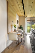 Deska jídelního stolu organicky navazuje na dřevěné obložení stěn a stropu.