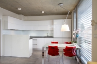 Přiznaný železobetonový strop, velkoformátová dlažba s „betonovým“ vzhledem a jednoduchý interiér v bílém provedení s několika červenými akcenty naznačují střízlivý moderní vkus majitelů domu.