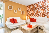 Společný obývací prostor prohřívá nejen sluníčko, ale i nátěr na stěnách v meruňkovém odstínu. Doplňuje jej tapeta s efektním retro vzorem. Kombinace oranžové a bílé působí dynamickým dojmem.