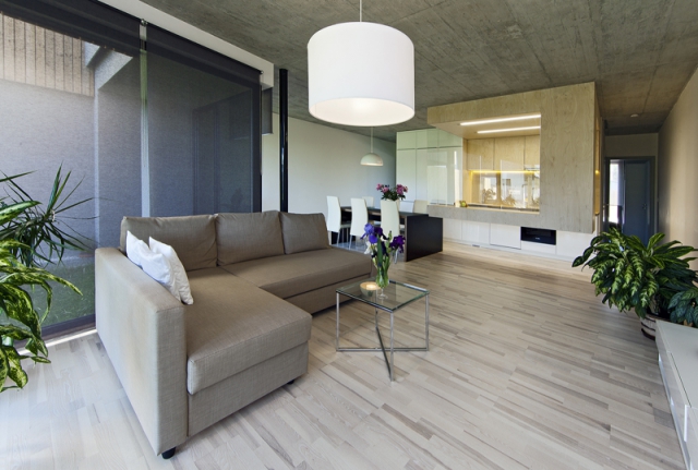 Společný obývací prostor zaujímá téměř dvě třetiny plochy přízemí. Základní tón interiéru udává kontrast betonového stropu a podlahy z krásného olejovaného jasanu.
