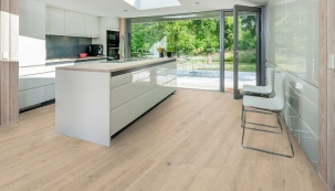 Protáhlý světlý interiér se s měnící se barvou dřevěné podlahy Kährs proměnil v opticky menší, teplejší prostor s výrazným kuchyňským ostrůvkem (zdroj: KPP)