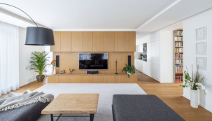 Velkorysý obývací prostor je rozdělen nábytkovou stěnou s televizí na obývací pokoj a kuchyň s jídelnou. Toto řešení je běžné i u řady rodinných domů
