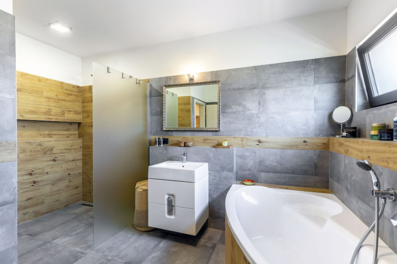Velká a prostorná koupelna kombinuje dřevo s obklady se vzhledem betonu