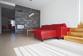 Podlahu v celém přízemí pokrývá velkoformátová keramická dlažba. Architekt ji použil také na obložení dělicí stěny, antracitový obklad s metalizujícím efektem je proveden záměrně beze spár, aby působil jako ocelový plech