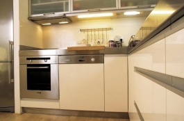 Design linky klade důraz na jednoduché tvary a odolné povrchy. Architekti zvolili nerez ocel (pracovní deska, sokly) a MDF desky s vysoce odolnou lesklou fólií (dvířka, obklad stěny) smetanové barvy