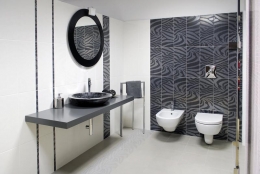 Výrazný obklad ve stylu art deco je použit na větší ploše jen na jedné stěně. Na druhé je do bílých obkladů zakomponovaný pouze jeden horizontální pás a dvě listely