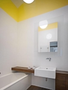 Koupelna je řešena velmi jednoduše. Bílé obklady doplněné dřevěným stolkem jsou elegantní a nadčasové