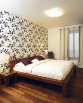 Stěna ložnice je opatřena luxusní kytičkovou tapetou