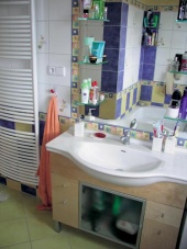 Poměrně malou koupelnu opticky zvětšuje velké zrcadlo, nedostatek úložného prostoru vyřešili zabudováním skříňky pod umyvadlo