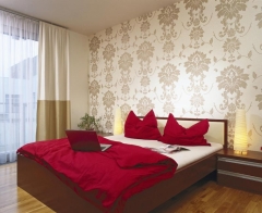 Ložnici zdobí výrazná tapeta, jak jinak než v módním dekoru a barevnosti