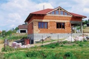 Pohled na rozestavěný dům a svažitý pozemek
