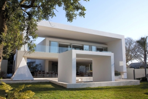 Před obytný dům ve tvaru jednoduché kompaktní krychle architekt předsadil v přízemí i v patře krytou terasu, jejíž konstrukci tvoří masivní železobetonový rám s hladkým bílým štukem. Analogický tvar má i plastika v okrasné vodní ploše. Vznikl tak velmi výrazný plastický efekt.