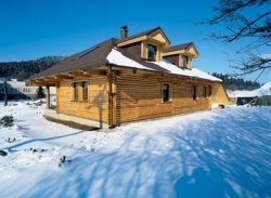 Dřevostavba dokonale zapadá do okolní přírody (v pozadí za střechou hrad Přimda)