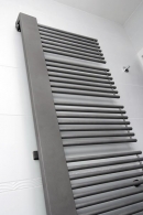 Otopný žebřík v provedení matného nerezu designově dobře zapadá do celého prostoru koupelny