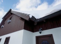 Od sněhových peřin a bílé strukturální omítky se odrážejí tmavě namořené palubky podkroví