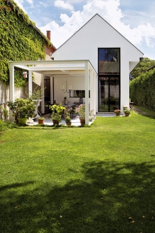 Pergola poskytuje další místo pro relaxaci a venkovní stolování. Díky velkému oknu má dům z této strany moderní tvář.