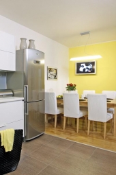 Jídelní stůl a židle (vše IKEA) zatím zůstaly z původní verze kuchyně, ale čeká je „omlazení“, nad stolem je zavěšeno elegantní skleněné svítidlo (RENDL LIGHT STUDIO), které nezakrývá pohled na televizi, na podlaze zůstaly původní dubové parkety