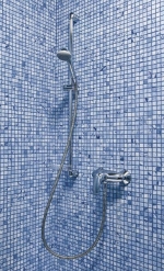 Na zdi je připevněn sprchový set se sprchovou baterií od firmy GROHE