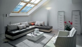 Prostorný obývací pokoj je zařízen jednoduše, ale elegantně: rohová sedací souprava Nomade, dvě komody Contours, stolek Pluriel, koberec Nature, křeslo Facett (LIGNE ROSET)