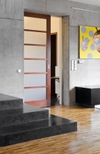 Kombinace teakové podlahy, pohledového betonu, teraca a skla působí velmi elegantně