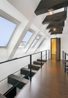 Halu v podkroví prosvětlují dvě řady střešních oken Velux umístěné v rovnoběžných liniích nad sebou. Proti přehřívání prostor chrání vnitřní zastiňovací rolety na dálkové ovládání, barevně sladěné s rámy oken 