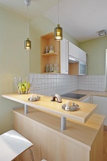Světlou kuchyň v minimalistickém designu od ostatního prostoru opticky odděluje barový pult, který může sloužit také jako odkládací plocha