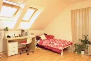 Do dívčího pokoje s částečně zkosenými stěnami přivádí světlo střešní okna VELUX a francouzské okno umístěné ve štítové zdi