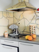 Digestoř obložená stejným materiálem, jako je obklad na stěně, působí zajímavě. Nezbytné espresso zde určitě není na ozdobu