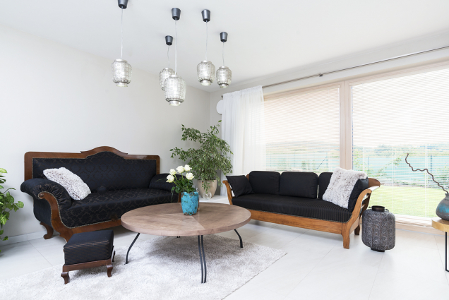Obývací pokoj má díky velké rohové prosklené ploše panoramatický výhled a bohatou záplavu světla. Historické sofa působí v moderním domě velmi půvabně.