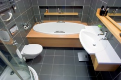 Z bývalého WC a předsíně se "vyloupla" koupelna. Přestože je obložena šedým obkladem, nejde o žádnou šedivou myšku, ale o komfortní místnost, kam se vešla vana i sprchový kout