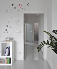 Lesklá podlaha vytváří zajímavý zrcadlový efekt. Bílé stěny jsou dekorovány tapetami (Lars Kontzen) a nálepkami ve tvaru písmen (Wise Decor).