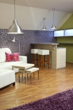 Elegantní tmavě fialovou tapetu se stříbrným efektem perfektně doplňuje svěží žlutozelenošedý odstín na stěnách, který zároveň rozjasňuje celý interiér. Šikmé stropy a štítová zeď s okny jsou bílé