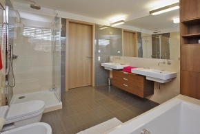 V celém domě architekti dbali na dostatek úložného prostoru. Do koupelny, vybavené elegantní italskou sanitární keramikou, navrhli sestavu skříněk s teakovou dýhou
