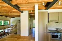 Kuchyňská linka vyrobená na zakázku z laminovaných MDF desek se ukrývá za polopříčkou. Fotografie naznačuje, že architekt dbal i na zajímavé průhledy 