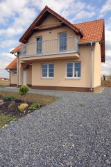 Prostorný balkon zdobí dům i z druhé strany. Obývací pokoj pod ním nabízí příjemný výstup na částečně krytou terasu
