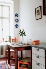 Jednoduchá kuchyň v úzké chodbě je vybavená starožitným jídelním stolkem se židlemi a malou kuchyňskou sestavou z IKEA