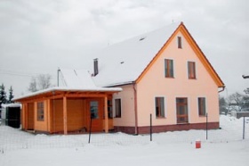 Rodinný dům s energeticky úspornými prvky v Černošicích. Sedlovou střechu tvoří vaznicový krov. Příčka okolo schodiště a v kuchyni je ponechána pohledově jako režná. Realizace: Alterstav, s. r. o.