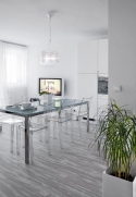 Útulné místnosti - tedy obývacímu pokoji s kuchyňským koutem dominuje velký stůl s transparentními židlemi La Marie (Kartell) od Philippa Starca a osvětlení Bourgie, design Ferruccio Laviani (Kartell)