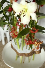 Řez z kmene stromu nepatří k obvyklým vázám, ale tuto kytici drží spolehlivě pohromadě. Dlouhé stonky lilií a gladiol stojí v misce s vodou, aby neuvadly (Lilium, Viburnum, Gladiolus)