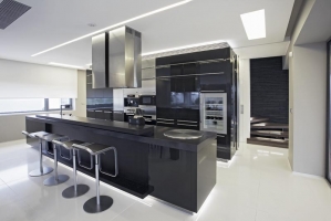 Na přání majitelů je kuchyň v černém laku ve vysokém lesku. V kombinaci s bílou dlažbou a velkorysým prostorem působí výsledek elegantně