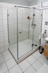 Elegantní sprchový kout s obdélníkovou vaničkou má zástěnu z čirého skla