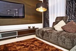 Na stěnu v obývacím pokoji použila designérka teplou temně hnědou barvu, aby LCD televizor příliš nevyčníval do prostoru a pocit pohledu na stěnu působil příjemně