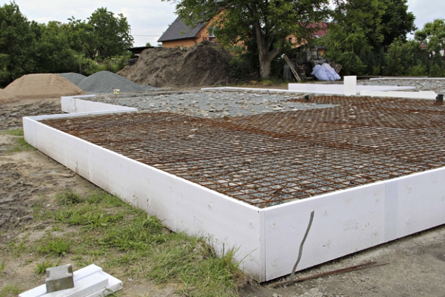 Po položení kanalizace se prostor pod domem vyplnil zhutněnou drtí, svislé výztužné tyče se zohýbaly směrem dovnitř, položily kari sítě a provedla betonáž základové desky (2)