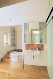 Půvabná koupelna se rozprostírá ve dvou úrovních a dokonce umožňuje přímý vstup na balkon