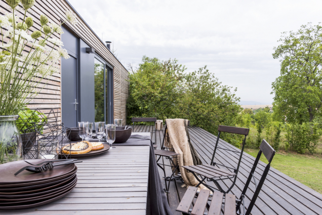 Na východní terase z modřínového dřeva kralují velký jídelní stůl (Ikea) a staré těžké skládací židličky, které architektku provázejí od dětství.