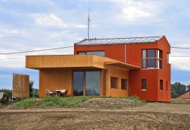 Architektonický výraz domu sází na kontrasty. Směrem k ulici se tyčí dvoupodlažní hmota s výraznou červenou omítkou, do zahrady směřuje přízemní přístavba s dřevěným obložením. Na jižní fasádu architekt navrhl atypický dřevěný slunolam